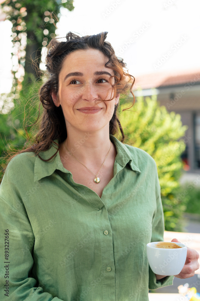 Smiling woman in green shirt holding coffee cup Smiling woman in green shirt holding coffee cup