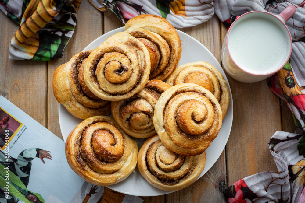 Fototapeta premium Vanilla buns with cinnamon. Sweet buns for breakfast on a wooden background. Homemade cinnamon rolls. View from above. Close-up
