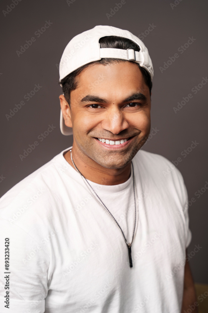 Happy DJ wearing cap and standing against brown background Happy DJ wearing cap and standing against brown background