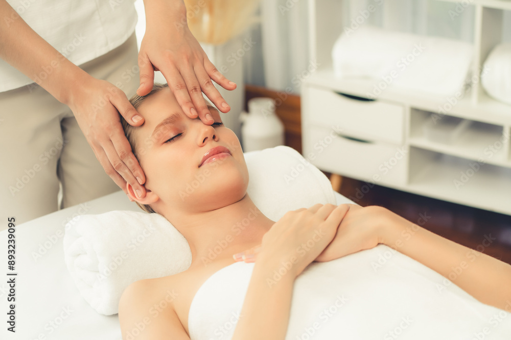 Fototapeta premium Caucasian woman enjoying relaxing anti-stress head massage and pampering facial beauty skin recreation leisure in dayspa modern light ambient at luxury resort or hotel spa salon. Quiescent