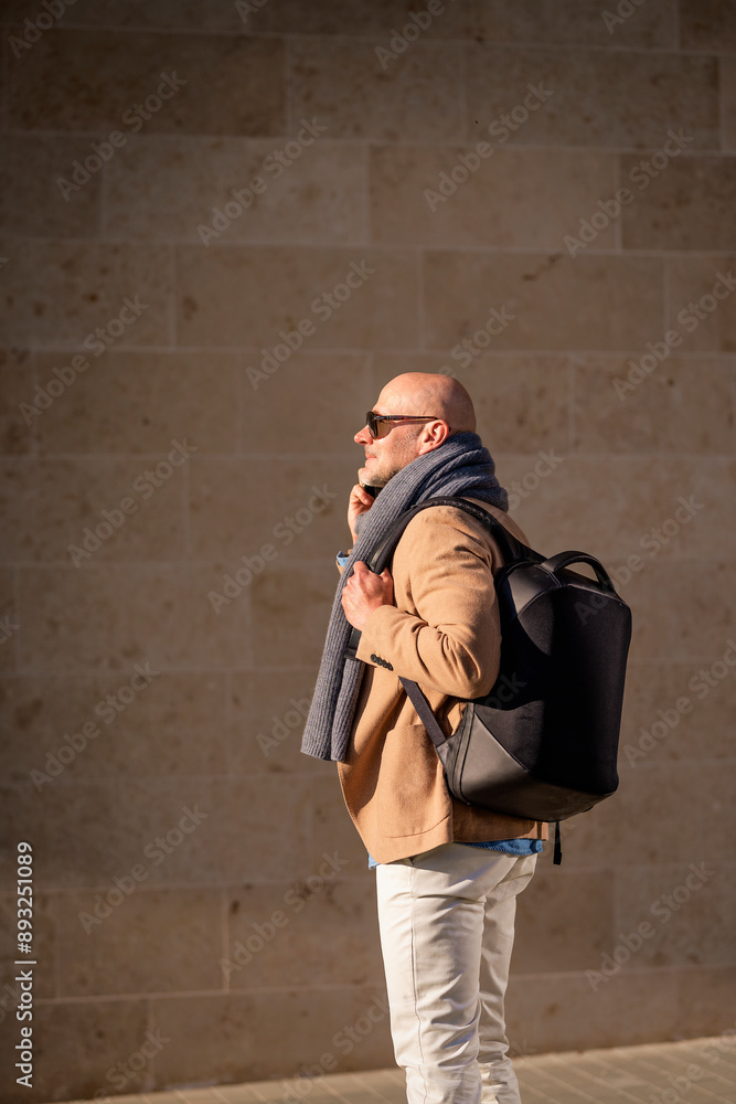Naklejka premium Mid aged man with mobile phone walking down the street