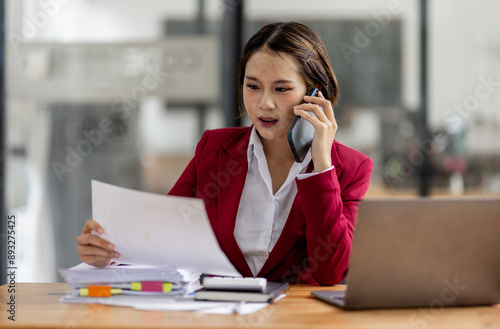 Cheerful business Asian woman accounting making telephone call share good news about project working in office workplace, business finance concept.  © David