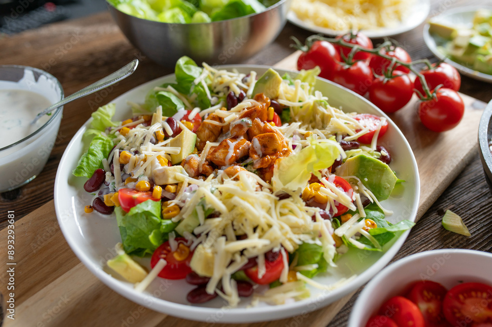 Tex mex barbecue chicken salad with kidney beans, avocado, cheese, lettuce, tomatoes, corn and ranch dressing on a plate Tex mex barbecue chicken salad with kidney beans, avocado, cheese, lettuce, tomatoes, corn and ranch dressing on a plate