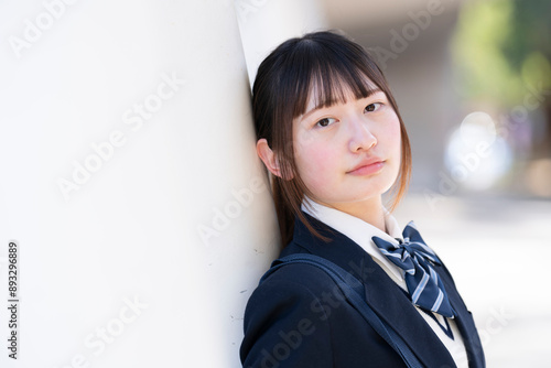 壁にもたれかかっている制服姿の女子学生 photo