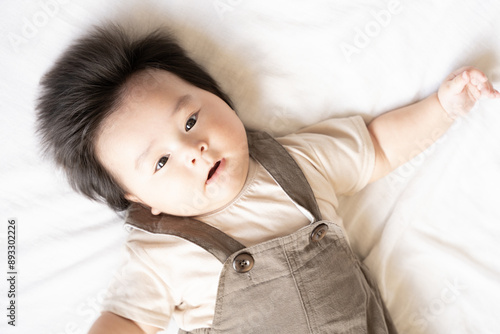布団の上で仰向けでこちらを見ている赤ちゃん