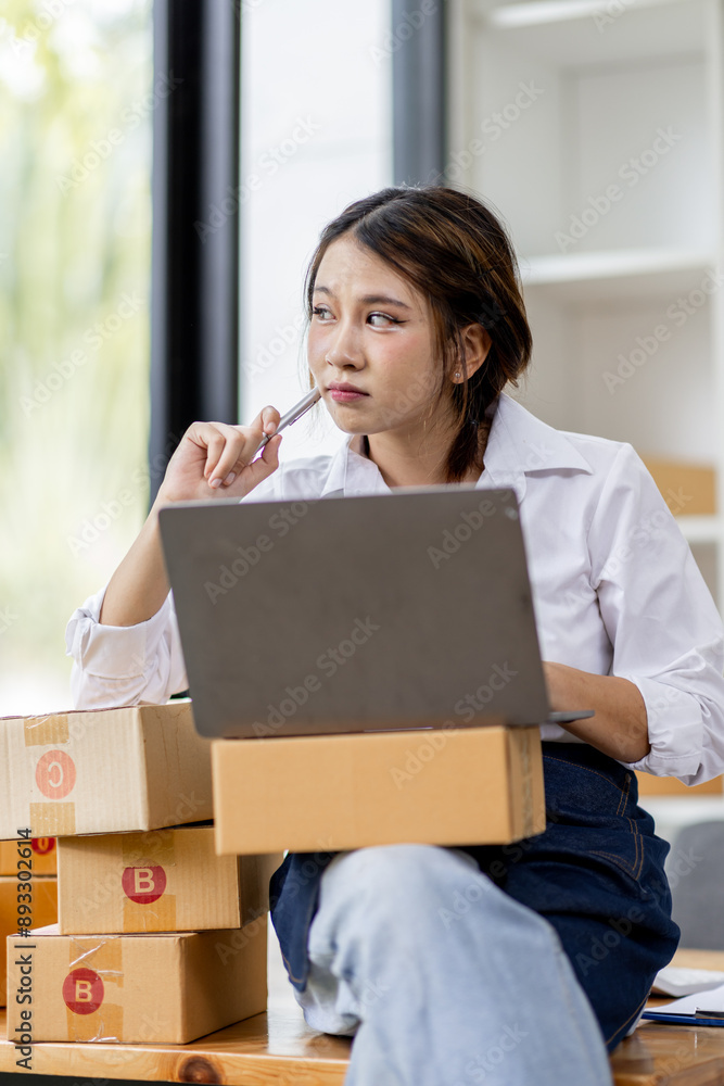 Portrait business woman smile and use laptop checking information on parcel shipping box before send to customer. Entrepreneur small business working at home. SME business online marketing. Portrait business woman smile and use laptop checking information on parcel shipping box before send to customer. Entrepreneur small business working at home. SME business online marketing.