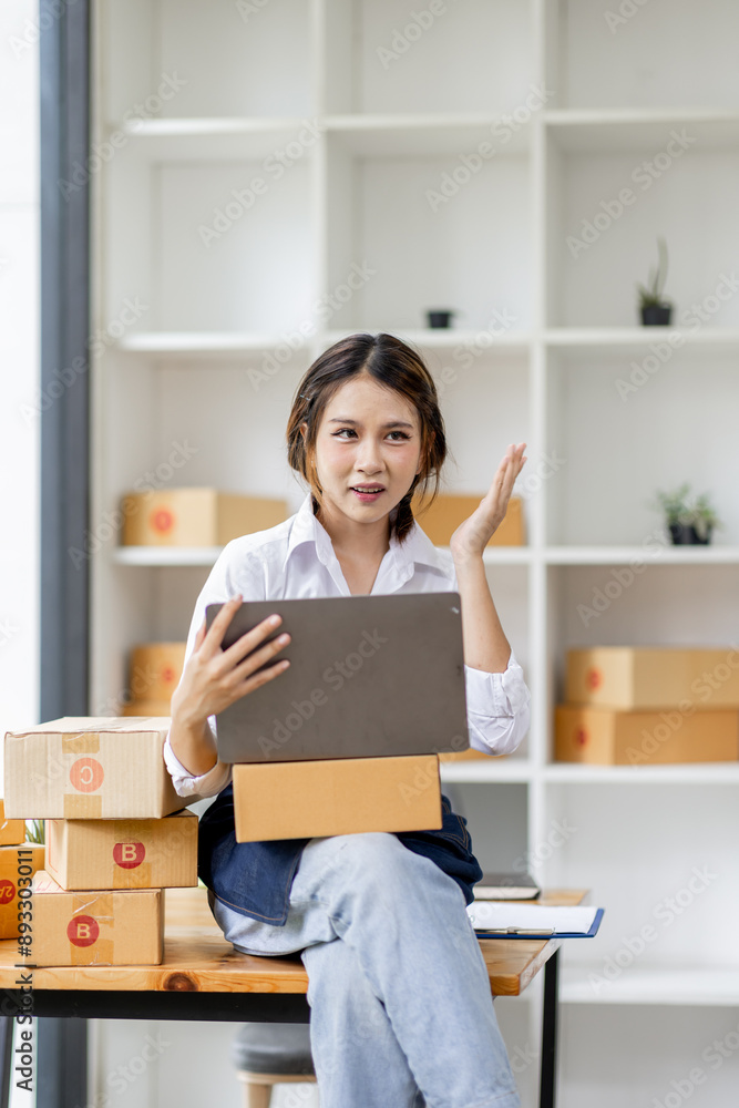 Portrait business woman smile and use laptop checking information on parcel shipping box before send to customer. Entrepreneur small business working at home. SME business online marketing. Portrait business woman smile and use laptop checking information on parcel shipping box before send to customer. Entrepreneur small business working at home. SME business online marketing.