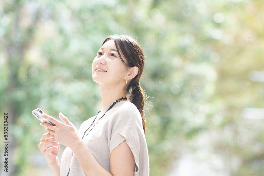 屋外でスマホを持っている女性のビジネスイメージ