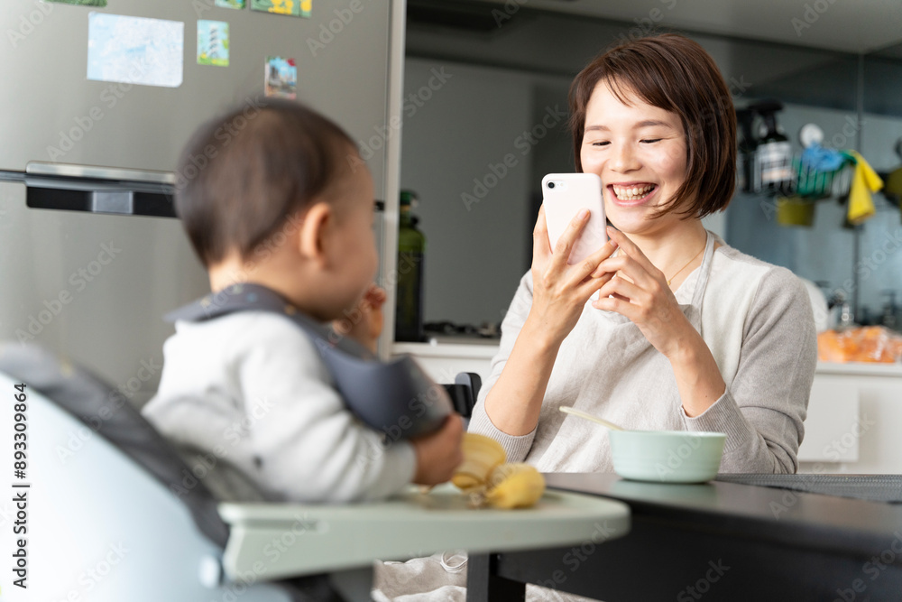 スマホで赤ちゃんの写真を撮っている笑顔の女性 スマホで赤ちゃんの写真を撮っている笑顔の女性