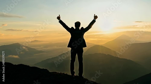 Triumphant businessman on mountain peak at sunrise