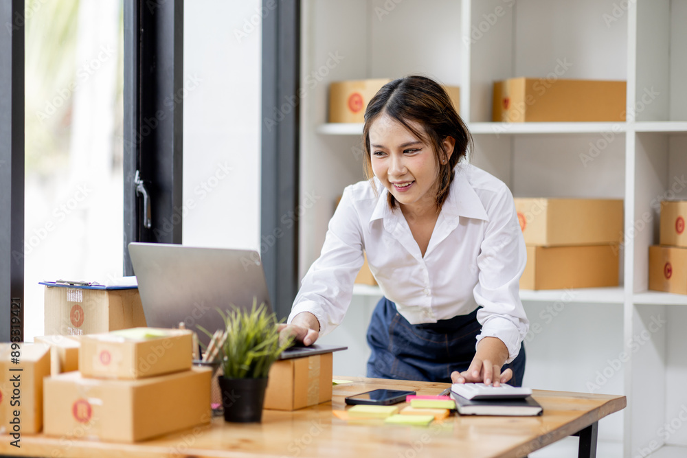 SME concept. Young asian female ecommerce business owner prepares package box for customer and delivery check balance. SME small business entrepreneur SME or freelance SME concept. Young asian female ecommerce business owner prepares package box for customer and delivery check balance. SME small business entrepreneur SME or freelance
