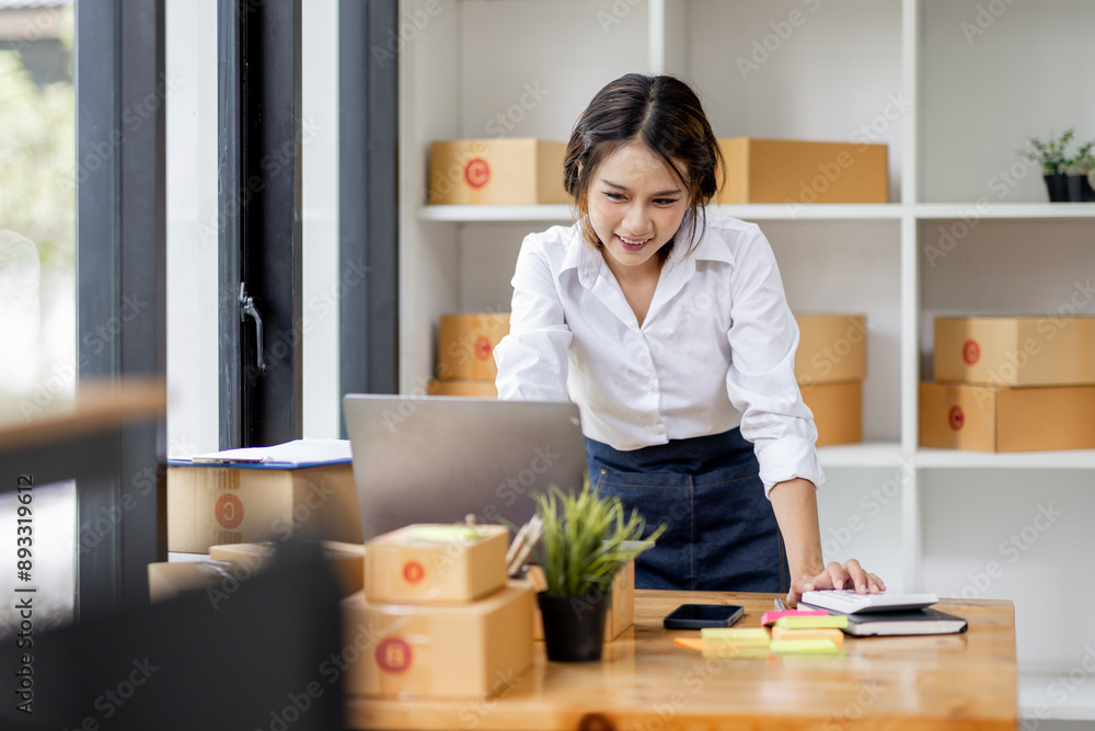 SME concept. Young asian female ecommerce business owner prepares package box for customer and delivery check balance. SME small business entrepreneur SME or freelance SME concept. Young asian female ecommerce business owner prepares package box for customer and delivery check balance. SME small business entrepreneur SME or freelance