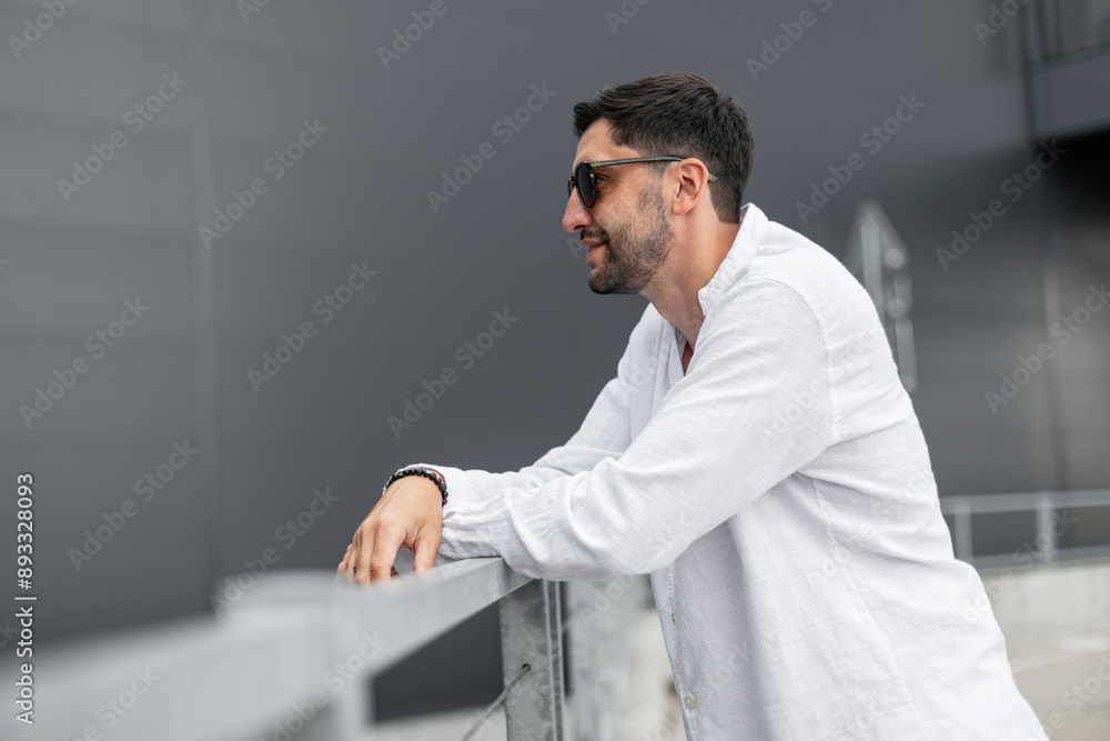 Handsome successful brutal business man in a fashion white shirt stands near a building in the city Handsome successful brutal business man in a fashion white shirt stands near a building in the city