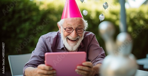 Obraz na płótnie Elderly man in party hat celebrates birthday outdoors, using tablet for digital connection and entertainment w salonie