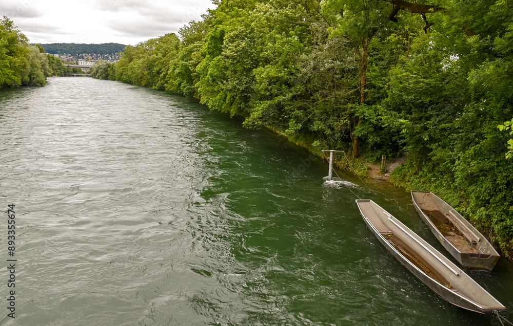 Scenic Limmat Riverbank in Zurich: Lush Greenery and Traditional Boats