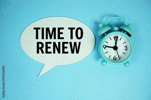 Time to Renew text on buble speech with alarm clock top view on blue background