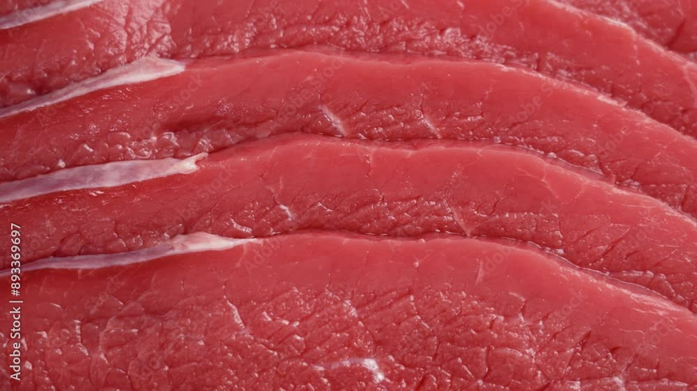 Raw beef slices are shown in a close-up shot highlighting texture of the red meat. Protein healthy food. Rotation Raw beef slices are shown in a close-up shot highlighting texture of the red meat. Protein healthy food. Rotation