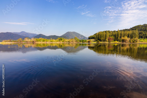 Beautiful landscape with reflection of mountain range on water at Tha Khoei reservoir in Ratchaburi, Thailand.
