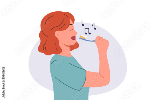 Teenage girl brushes teeth during morning wash and sings songs enjoying process of healing oral cavity. Cheerful woman brushes teeth to prevent caries and get rid of bad breath left after eating.