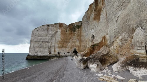 Landscape drone video of tall, steep limestone cliffs by the ocean with one with a hole in it creating an arch