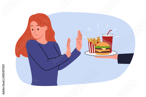 Refusal from fast food is demonstrated by woman who wants to go on diet and reduce amount of calories consumed. Girl turns away from tray with fast food in hands of interlocutor, demonstrating disgust