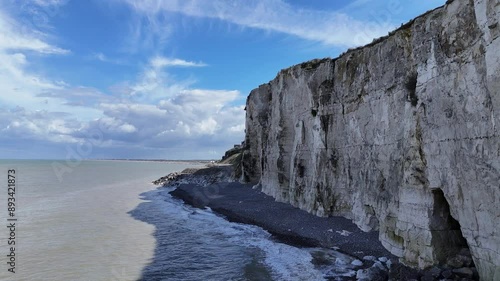 drone video footage of the chalk cliffs of etretat in France in Normandy with a blue sky with white clouds and the sea