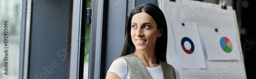 Cuadro en lienzo A young woman with long hair gazes out a window, pondering her startup's future