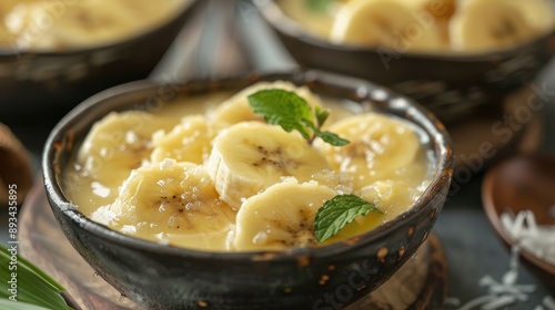 Close-up of Thai banana in syrup (kluay chuam) served in a bowl with coconut milk. photo