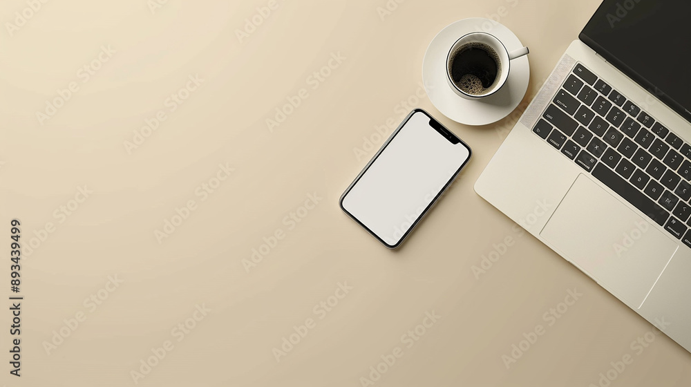 A minimalist home office setup featuring a laptop, smartphone, and cup of coffee against a beige background, ideal for business and work-from-home concepts.