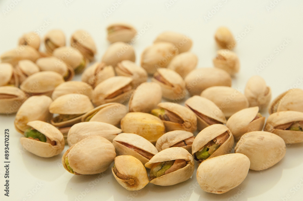 Shelled and unshelled pistachios on white background,hands holding some pistachios Shelled and unshelled pistachios on white background,hands holding some pistachios