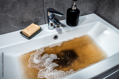 Tableau sur toile Clogged sink in bathroom, sink with dirty water, brown soap