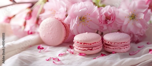Vintage tablecloth adorned with pink macaroons and a blooming cherry flower branch in the background creating a serene copy space image © Gular