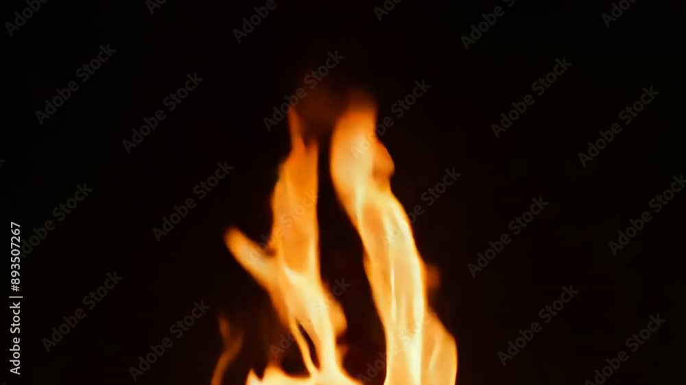 Intense close-up shot of bright, orange fire flames against a dark backdrop Intense close-up shot of bright, orange fire flames against a dark backdrop