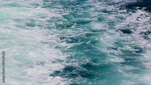 Whitecaps churn and swirl against the deep blue water of the ocean.