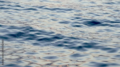 A close-up shot of the surface of the water as gentle waves create a rippling effect in the blue water.