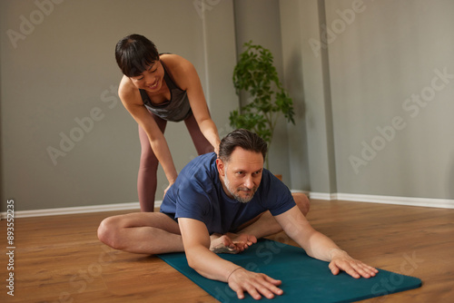 Woman assisting man with yoga stretch