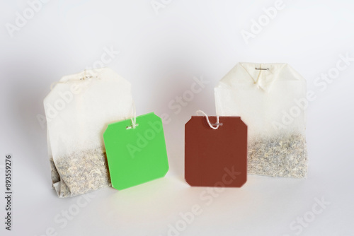 Two tea bags with empty labels of different colors on a white background. Template with blank tag on the theme of hot soft drinks.