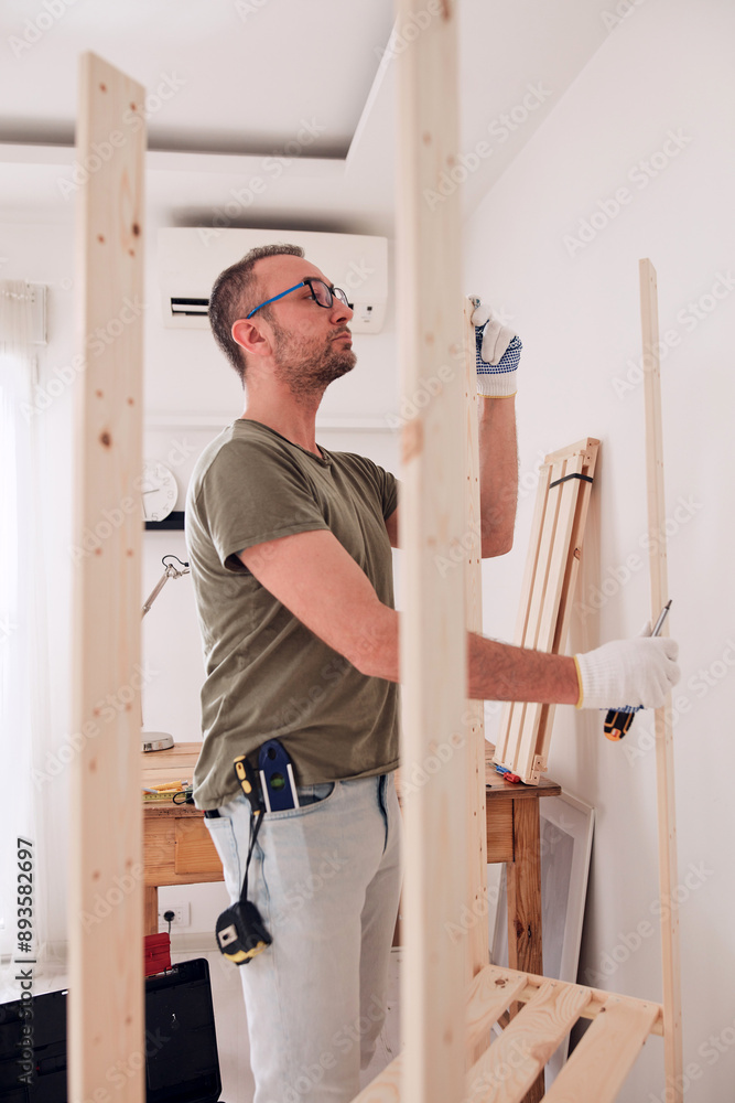 Man assembling new wooden shelf and furniture in the apartment. Man assembling new wooden shelf and furniture in the apartment.