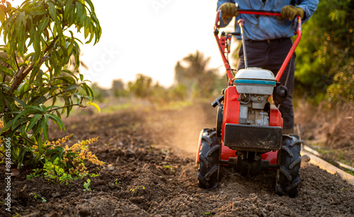 фотографія Farmer Using Rotary Tiller on a Plowed Field at Dawn