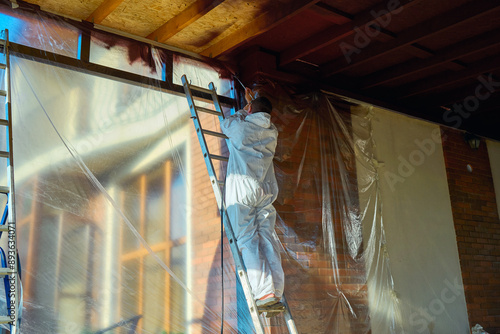 man paints a room with a spray gun photo