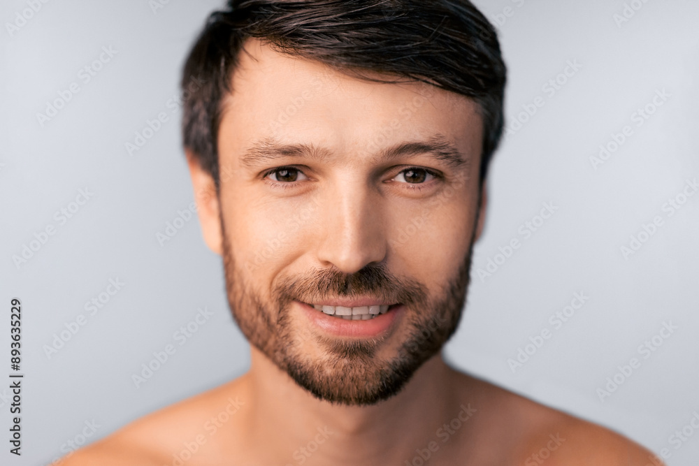 A close-up portrait of a man with short brown hair and a beard, smiling and looking directly at the camera. A close-up portrait of a man with short brown hair and a beard, smiling and looking directly at the camera.