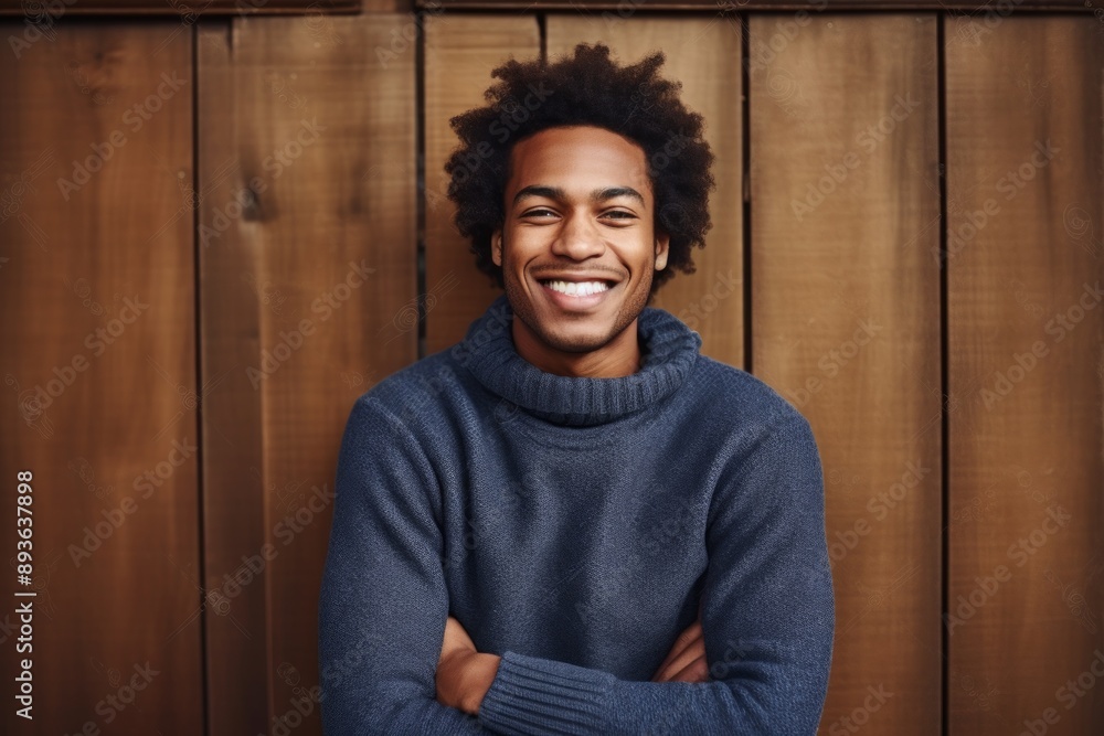 Portrait of a grinning afro-american man in his 30s dressed in a comfy fleece pullover while standing against rustic wooden wall Portrait of a grinning afro-american man in his 30s dressed in a comfy fleece pullover while standing against rustic wooden wall