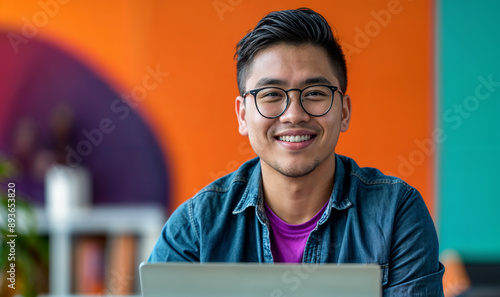 Wallpaper Mural young Filipino man working on laptop in a modern colorful office/ work from home, remote worker / digital nomad
 Torontodigital.ca