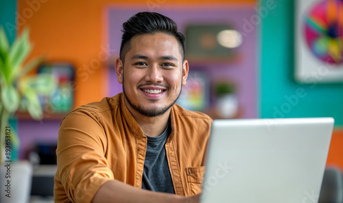 Wallpaper Mural young Filipino man working on laptop in a modern colorful office/ work from home, remote worker / digital nomad
 Torontodigital.ca
