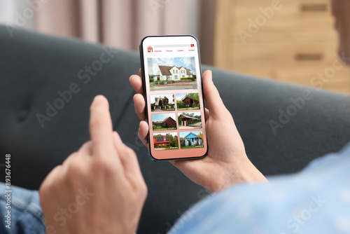фотографія Woman choosing dwelling on house hunting website via smartphone indoors, closeup