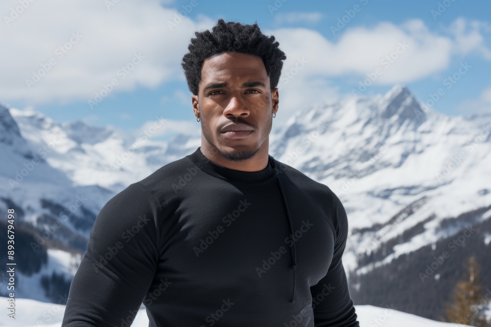 Portrait of a glad afro-american man in his 30s donning a trendy cropped top while standing against snowy mountain range Portrait of a glad afro-american man in his 30s donning a trendy cropped top while standing against snowy mountain range