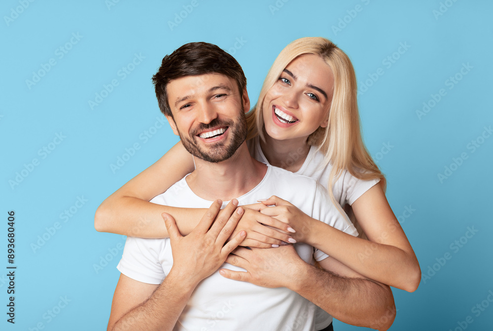 A man and a woman are smiling and hugging each other, with the woman's arms around the man's neck and her hands resting on his chest. They are both looking directly at the camera. A man and a woman are smiling and hugging each other, with the woman's arms around the man's neck and her hands resting on his chest. They are both looking directly at the camera.