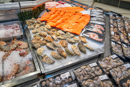 Foto Fresh seafood display with various shrimps, salmon fillet, oysters, clams, shellfish in grocery store