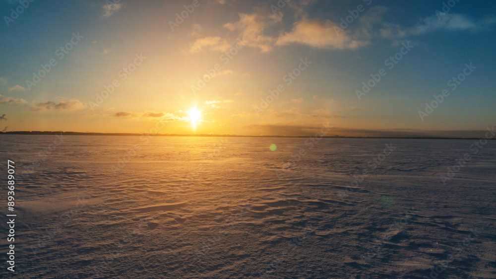 Frozen sea horizon at dawn with sunlight and snow-covered terrain Frozen sea horizon at dawn with sunlight and snow-covered terrain