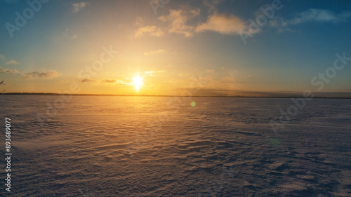 Frozen sea horizon at dawn with sunlight and snow-covered terrain